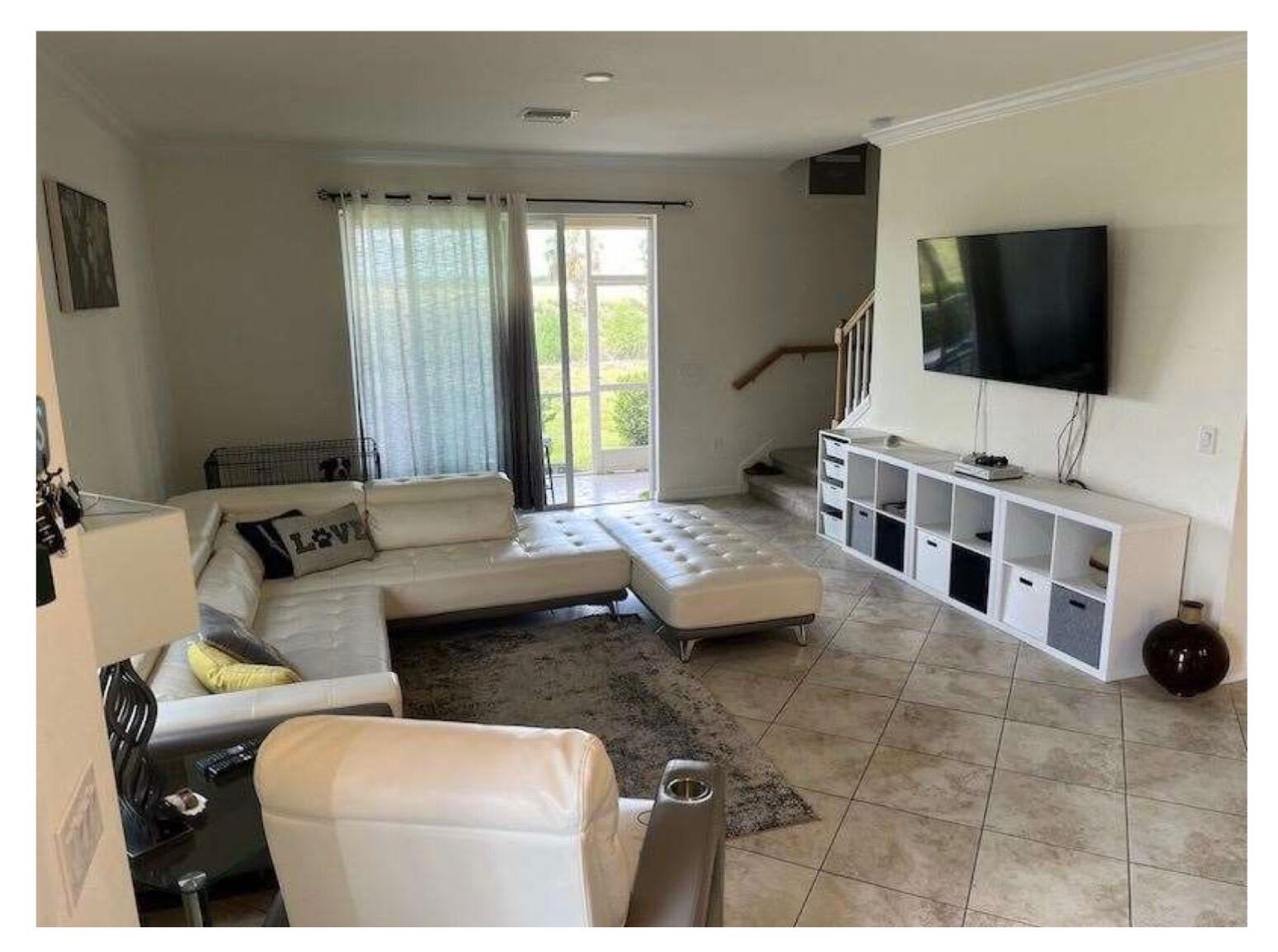 A living room with a white sectional sofa, tiled floors, and a wall-mounted television — 2763 Citrus Street, Naples FL 34120, NAPLES, FL