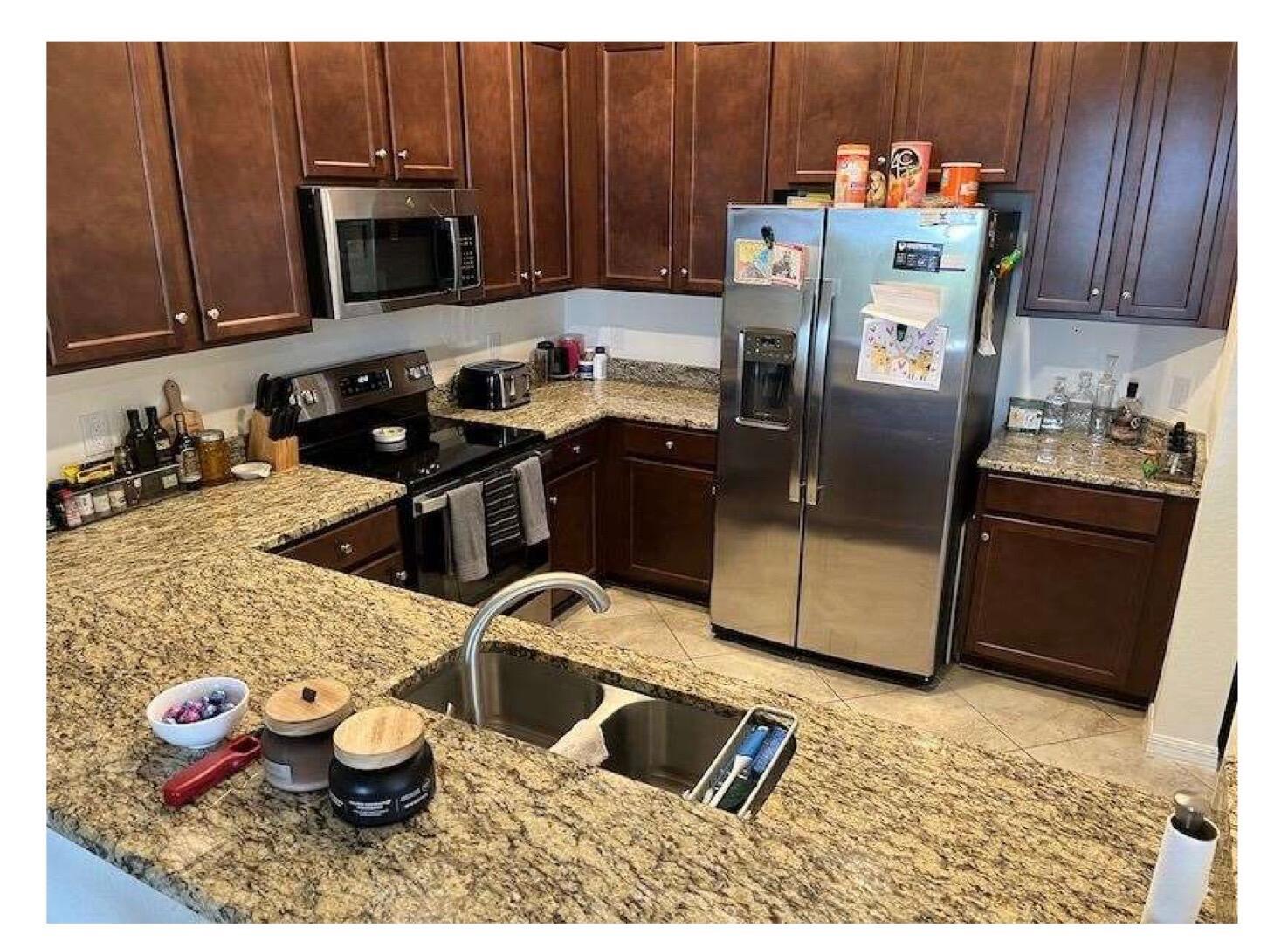A kitchen features dark wood cabinets, granite countertops, and stainless steel appliances — 2763 Citrus Street, Naples FL 34120, NAPLES, FL