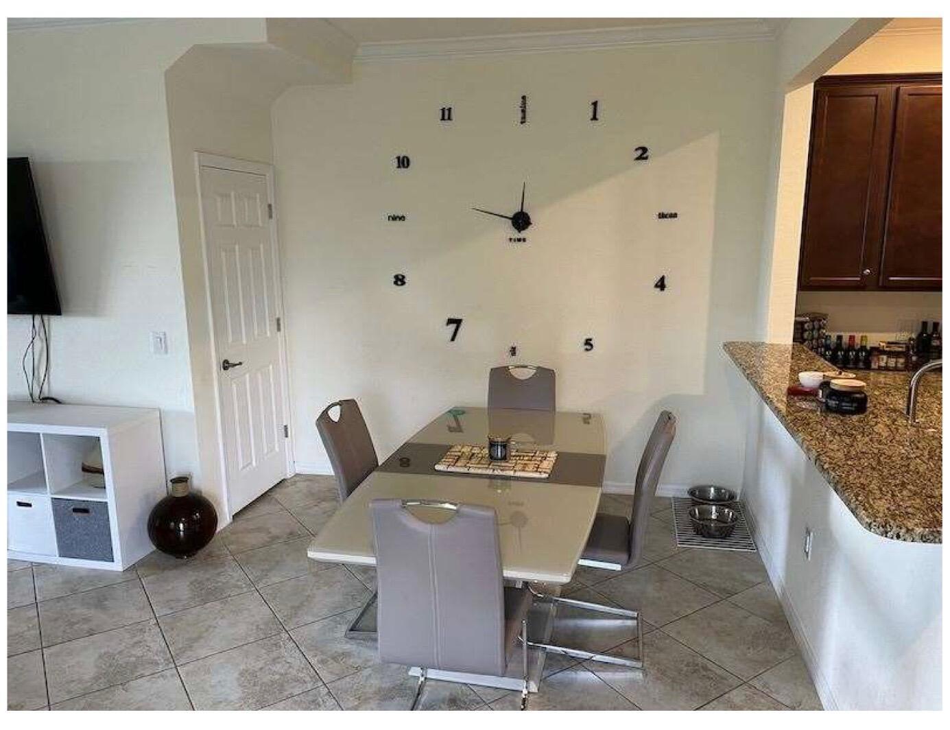 A dining area features a glass table, four chairs, and a large wall-mounted clock — 2763 Citrus Street, Naples FL 34120, NAPLES, FL