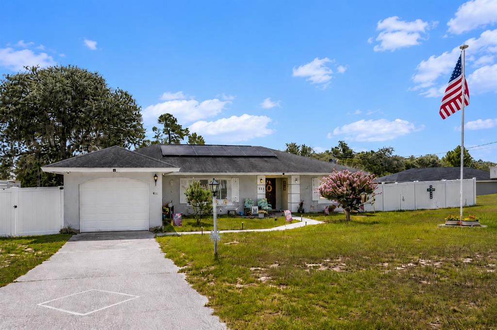 A single-story house with a white garage, solar panels, and an American flag in front — 124 OAK CIRCLE, OCALA, FL