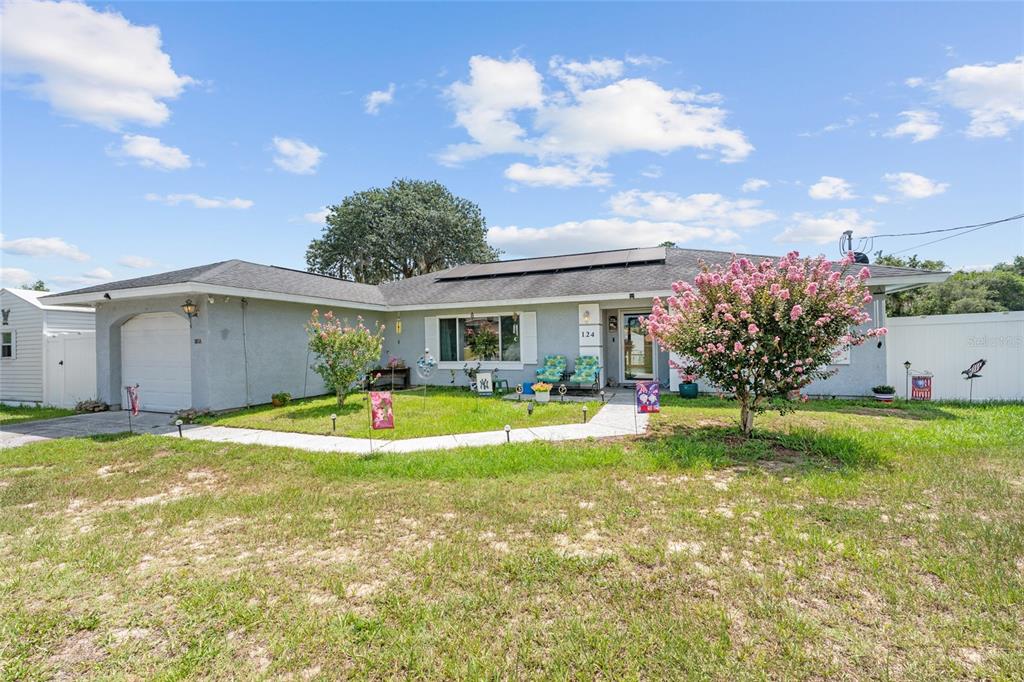 A single-story house with a gray exterior, a garage, and a front yard with trees — 124 OAK CIRCLE, OCALA, FL