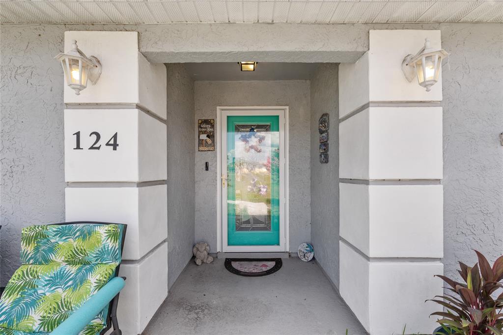 The front entrance features a teal door, white pillars with house number 124, and sconces — 124 OAK CIRCLE, OCALA, FL