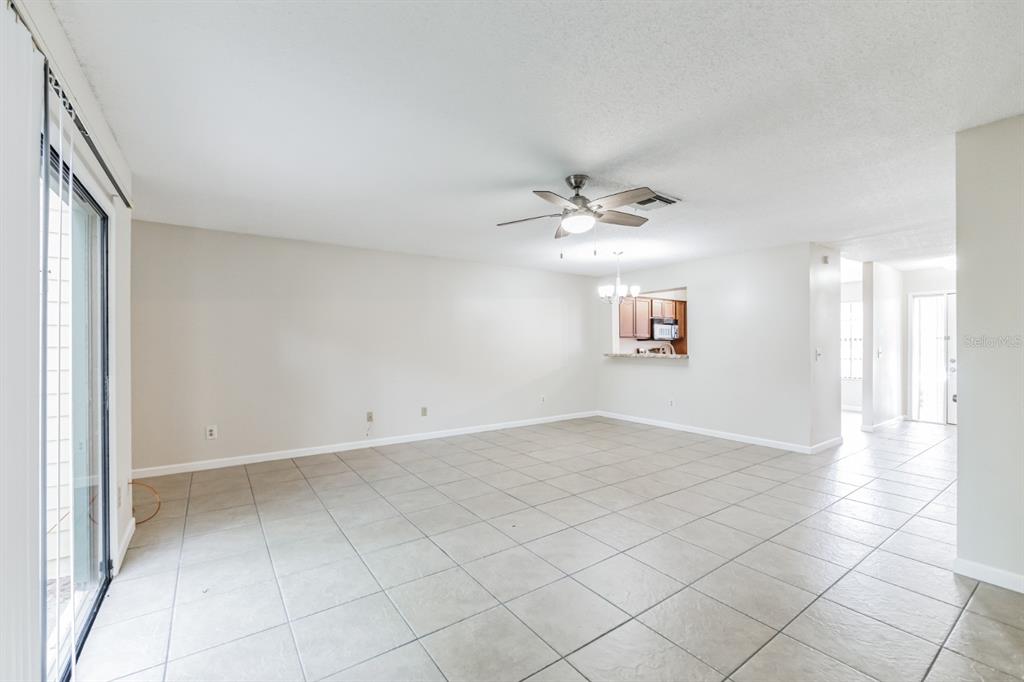 A spacious living room features light-colored tile flooring, a ceiling fan, and a kitchen pass-through — 2748 CANDLEWOOD COURT, APOPKA, FL
