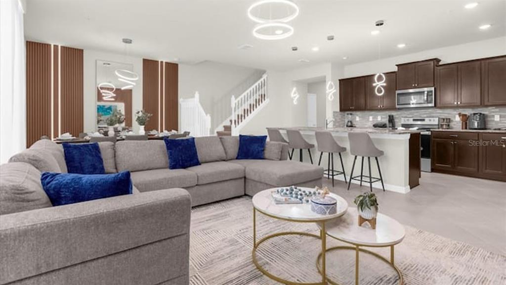 A spacious open-concept living room and kitchen featuring a grey sectional sofa and dark cabinetry — 1236 BLUE ISLAND DRIVE, CLERMONT, FL