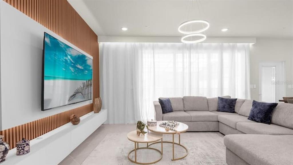 A living room features a wall-mounted television, a sectional sofa, and two nesting coffee tables — 1236 BLUE ISLAND DRIVE, CLERMONT, FL