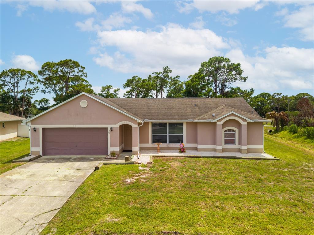 A single-story house with a tan stucco exterior, a two-car garage, and a shingled roof — 300 VIKING ST NE, PALM BAY, FL
