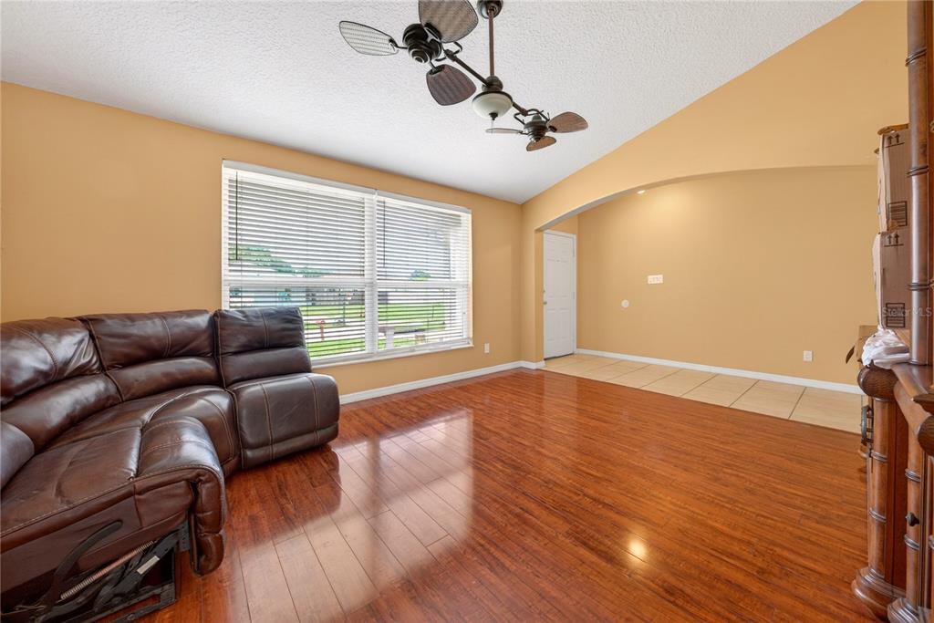 A living room features hardwood floors, a brown leather sectional, and a vaulted ceiling — 300 VIKING ST NE, PALM BAY, FL