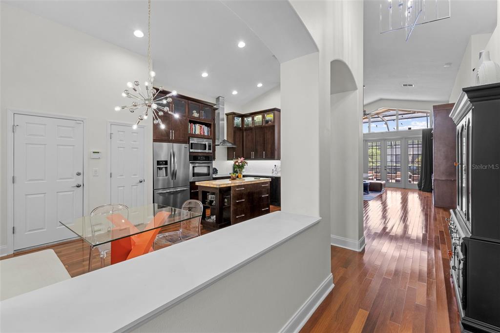 A kitchen with dark wood cabinets and a glass dining table viewed from a hallway — 1536 ABYSS DRIVE, ODESSA, FL