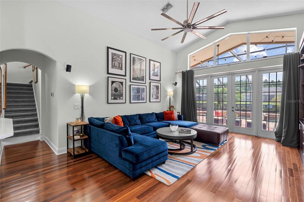 A living room features a blue sectional sofa, hardwood floors, and large windows with patio doors — 1536 ABYSS DRIVE, ODESSA, FL