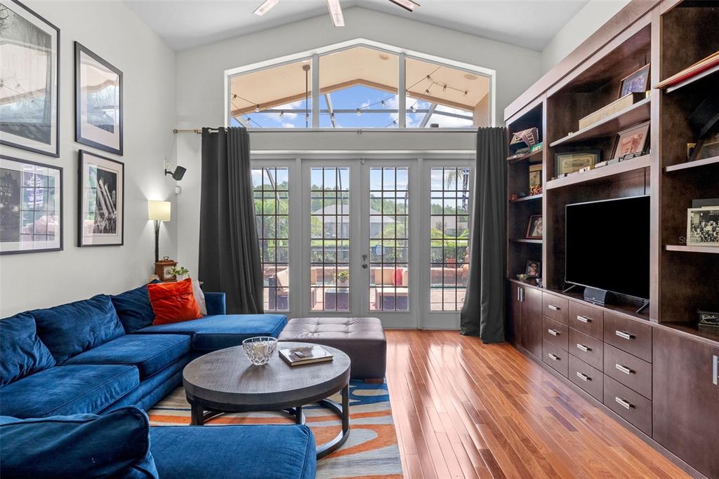 A living room features a blue sectional sofa, hardwood floors, and a large built-in bookshelf — 1536 ABYSS DRIVE, ODESSA, FL