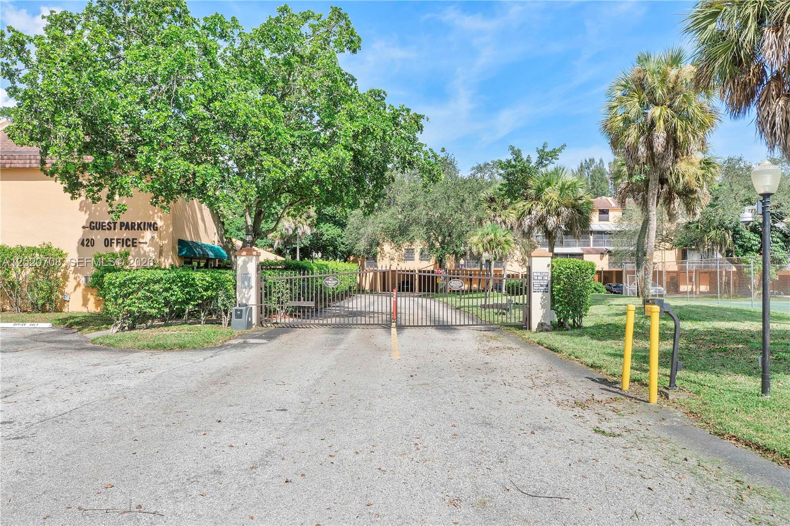 A gated entrance leads to a residential complex with guest parking and office signage — 430 Commodore Dr # 213, Plantation FL 33325, PLANTATION, FL
