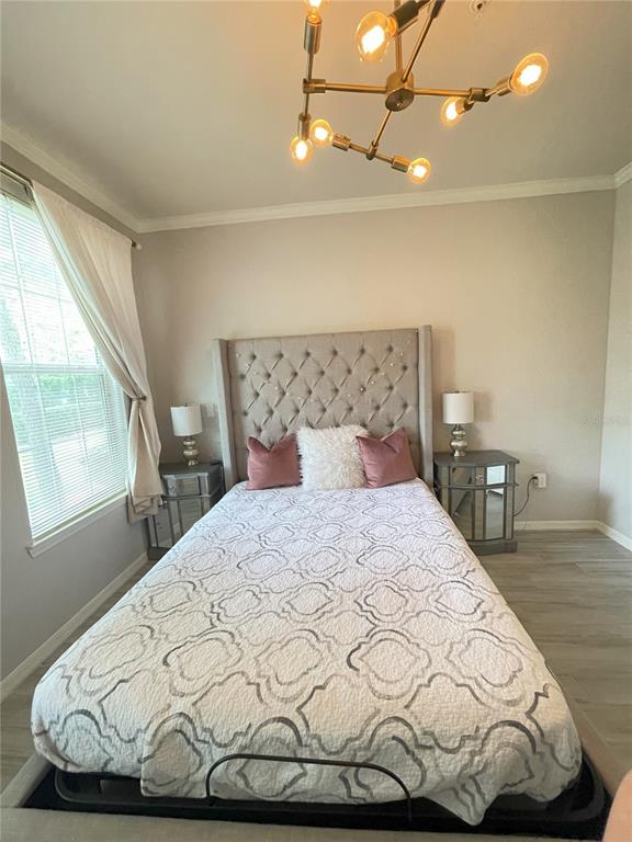 A bedroom features a tufted headboard, a patterned quilt, and a modern gold chandelier — 4221 W SPRUCE STREET UNIT 1107, TAMPA, FL
