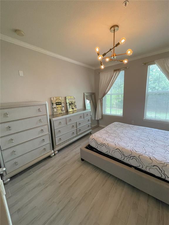 A bedroom features a bed, two dressers, a modern chandelier, and light-colored wood-look flooring — 4221 W SPRUCE STREET UNIT 1107, TAMPA, FL