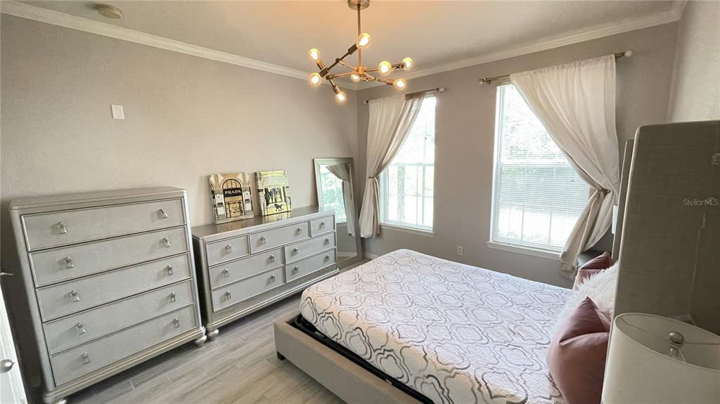 A bedroom features a bed, two dressers, a chandelier, and two windows with white curtains — 4221 W SPRUCE STREET UNIT 1107, TAMPA, FL