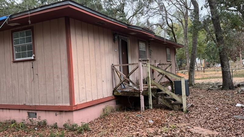 A single-story house with light-colored vertical siding and a wooden porch with stairs — 7415 BERNADETTE DRIVE, NAVARRE, FL