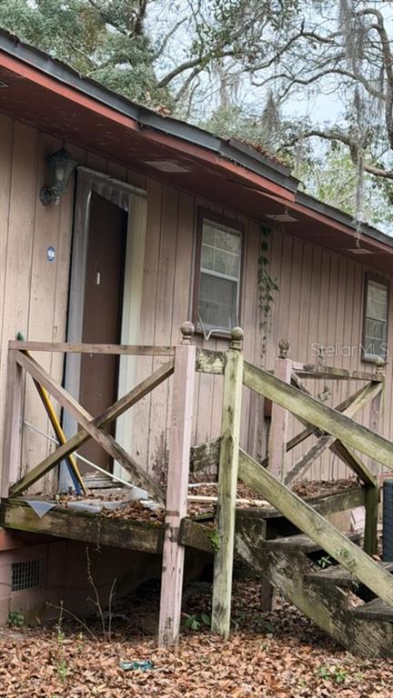 A weathered wooden porch with a staircase leads to the front door of a house — 7415 BERNADETTE DRIVE, NAVARRE, FL