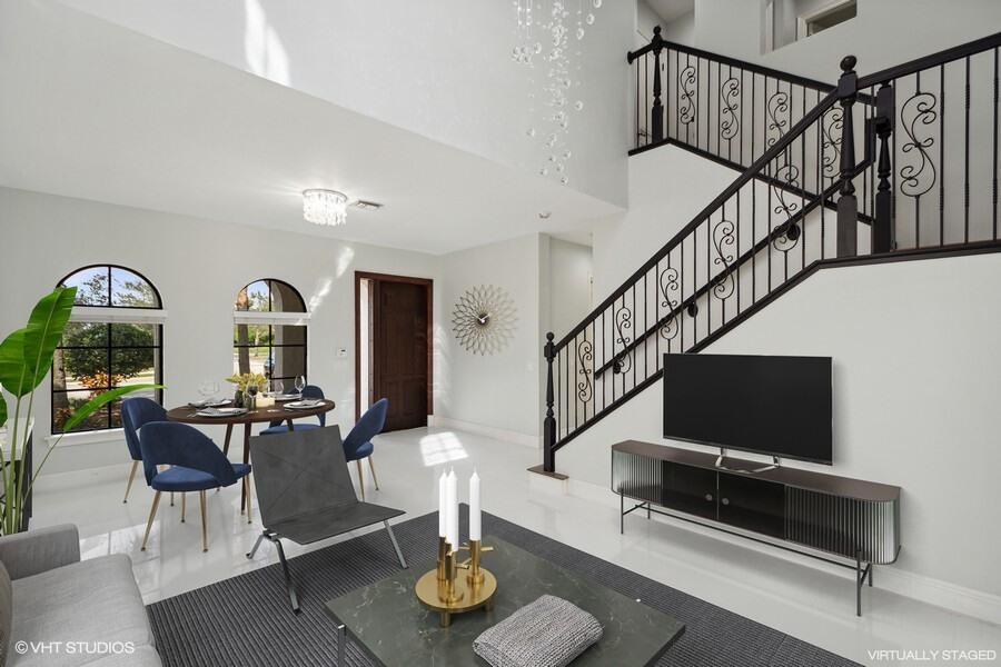 This living and dining area features a staircase with black railings and white tile flooring — 9648 Ginger Court, Parkland FL 33076, PARKLAND, FL