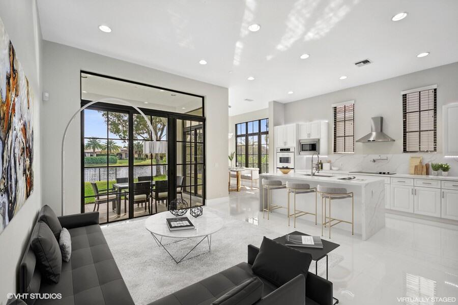 A modern open-concept living room and kitchen with white marble counters and black-framed glass doors — 9648 Ginger Court, Parkland FL 33076, PARKLAND, FL