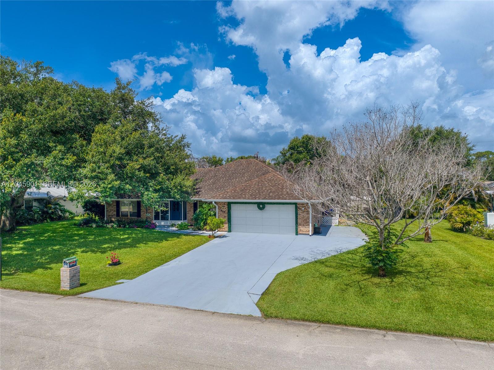 A single-story brick house features a two-car garage, a large lawn, and mature trees — 465 11th Ave, Vero Beach FL 32962, VERO BEACH, FL