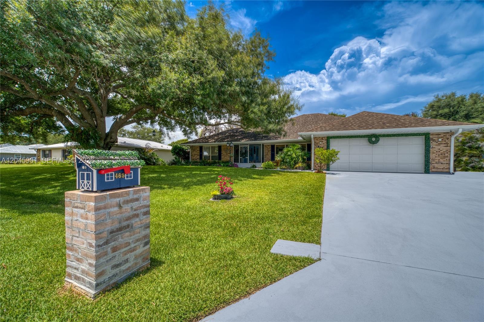 A single-story brick house with a two-car garage and a large tree in the yard — 465 11th Ave, Vero Beach FL 32962, VERO BEACH, FL