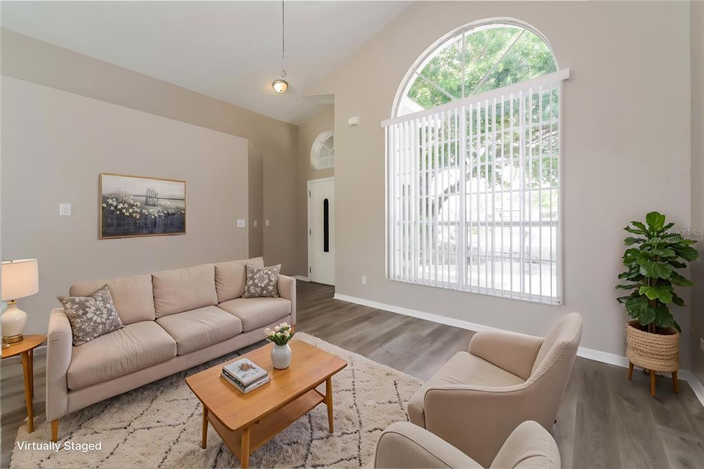 A living room with high ceilings, a large arched window, and wood-look flooring — 1003 DORKING WAY, KISSIMMEE, FL