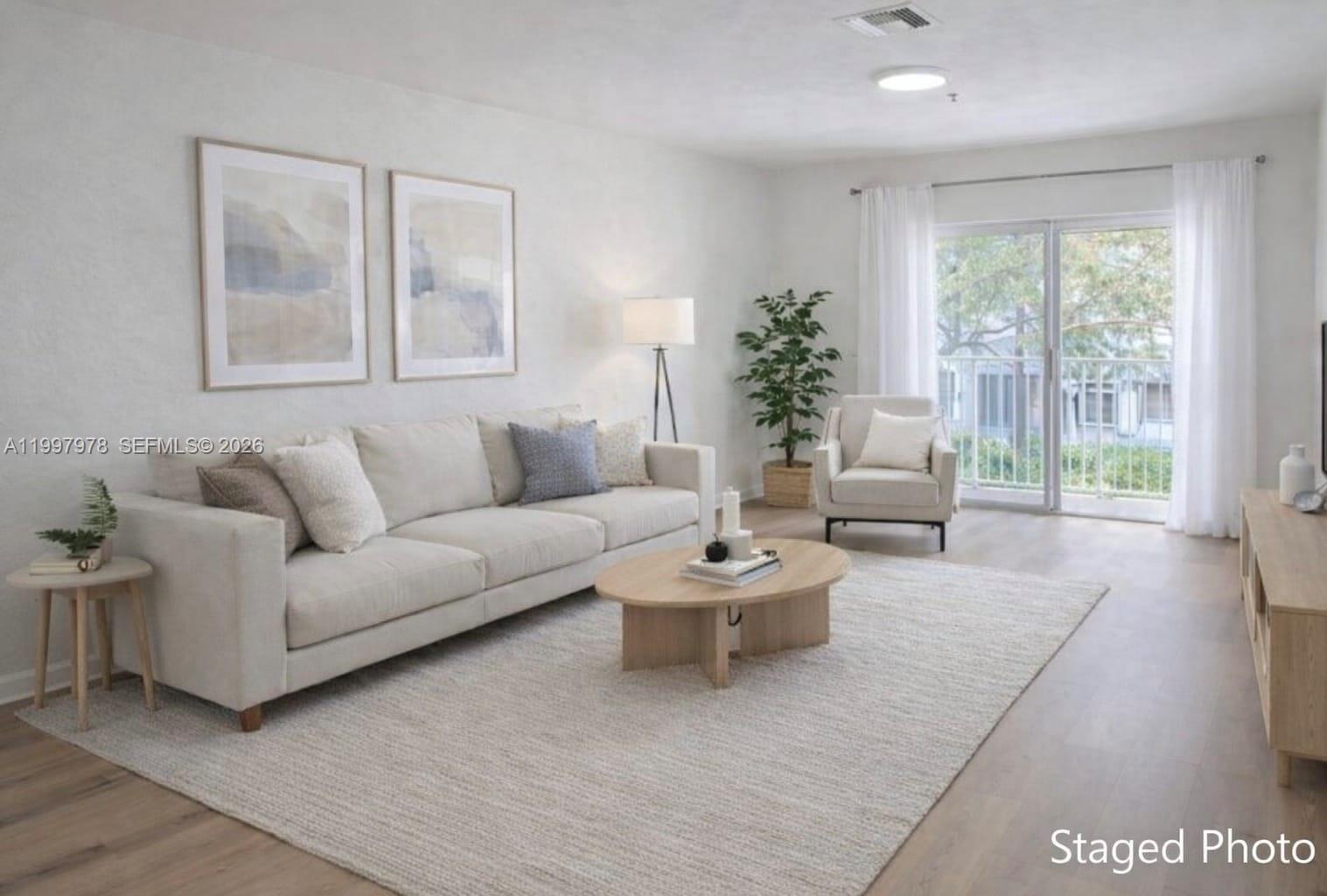 A staged living room features a beige sofa, oval coffee table, armchair, and sliding glass doors — 5640 NW 115th Ct # 211, Doral FL 33178, DORAL, FL