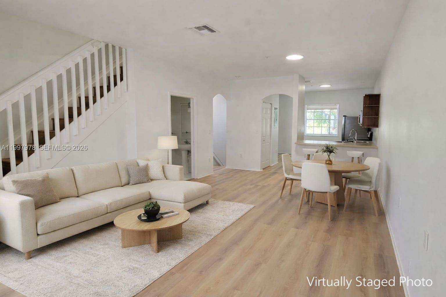 This virtually staged photo shows an open-concept living and dining area with light wood flooring — 5640 NW 115th Ct # 211, Doral FL 33178, DORAL, FL
