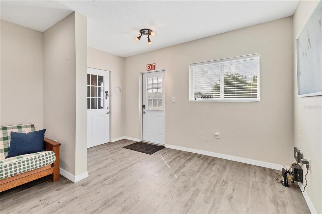 A room with light wood-look flooring, two white doors, a window, and a plaid chair — 3045 LOGUE ROAD, MYAKKA CITY, FL