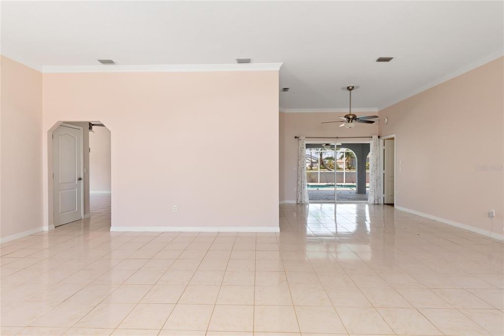 An open-concept living area with light-colored tile flooring and a view of a pool — 25332 RAMPART BOULEVARD, PUNTA GORDA, FL