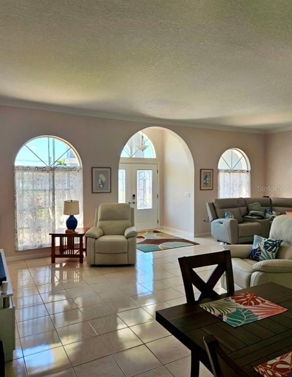 A living room with tile floors, arched windows, and a doorway leading to an entryway — 25332 RAMPART BOULEVARD, PUNTA GORDA, FL