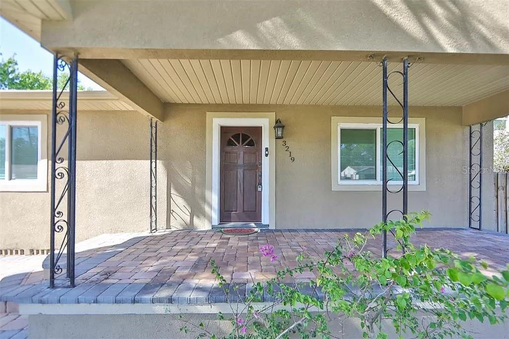 A front porch with brick pavers, decorative metal columns, and a brown front door — 3219 W LEROY STREET, TAMPA, FL