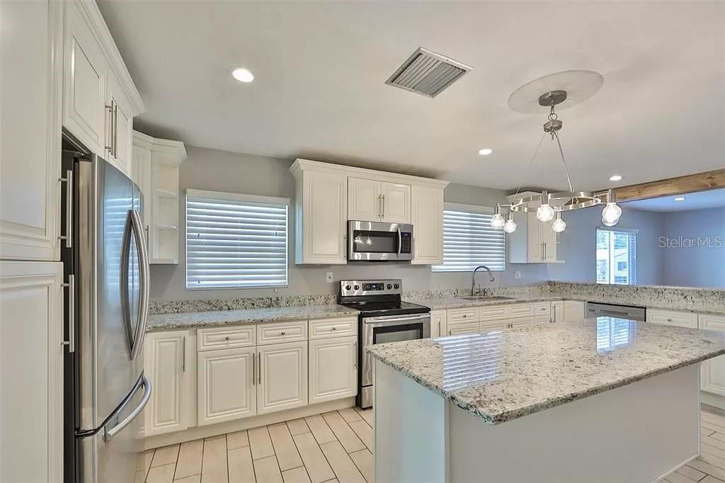 A kitchen features white cabinets, granite countertops, stainless steel appliances, and a central island — 3219 W LEROY STREET, TAMPA, FL