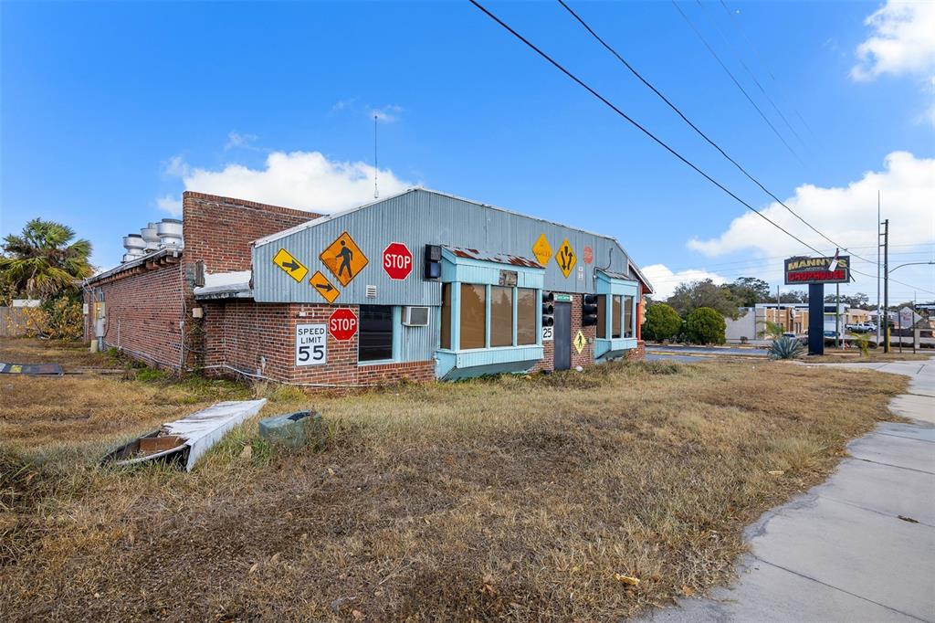 An exterior view of a weathered, single-story building decorated with various road signs — 210 STATE ROAD 60 W, LAKE WALES, FL