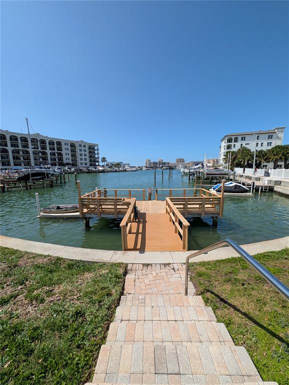 A wooden dock extends into a calm bay surrounded by multi-story residential buildings — 255 DOLPHIN POINT UNIT 505, CLEARWATER BEACH, FL
