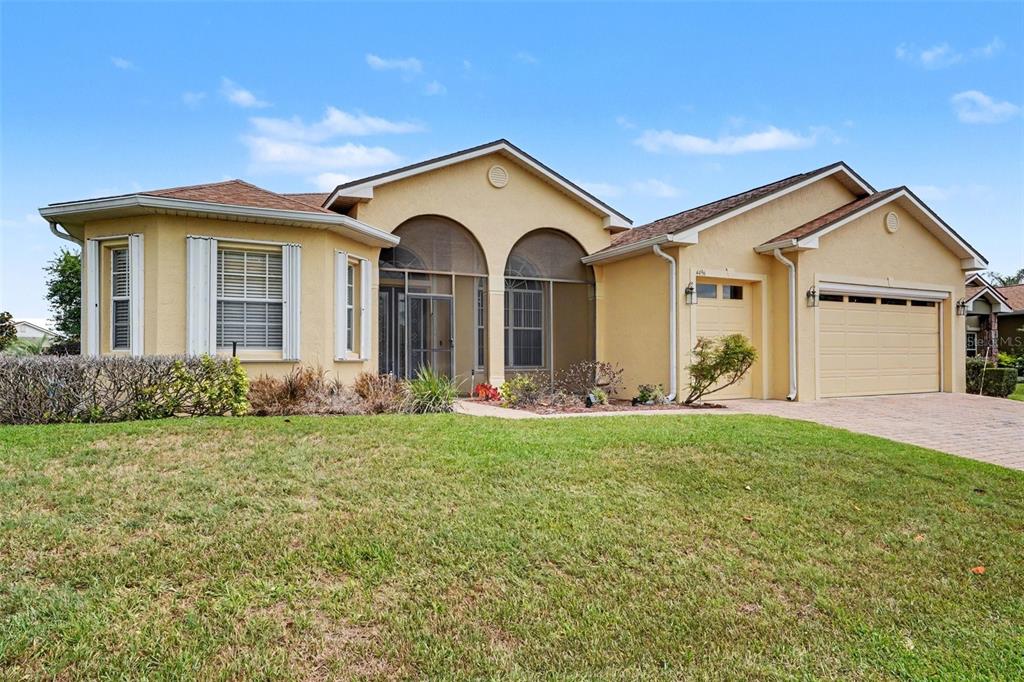 A single-story tan house with a screened entryway and an attached two-car garage — 4496 STRATHMORE DRIVE, LAKE WALES, FL