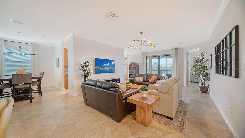 A living room and dining area with tile floors, neutral walls, and modern light fixtures — 6512 GRAND ESTUARY TRAIL UNIT 102, BRADENTON, FL