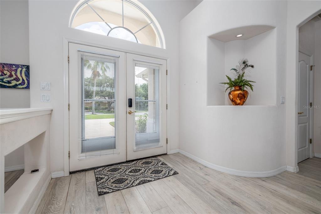 An entryway features double glass doors, light wood-look flooring, and a recessed wall niche — 100 PARADISE VALLEY COURT, DAYTONA BEACH, FL