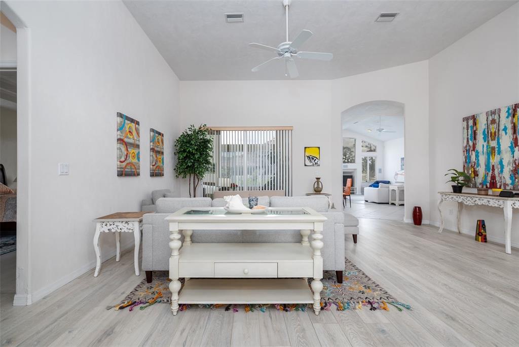 A living room with light wood flooring, a white sofa, and a central console table — 100 PARADISE VALLEY COURT, DAYTONA BEACH, FL