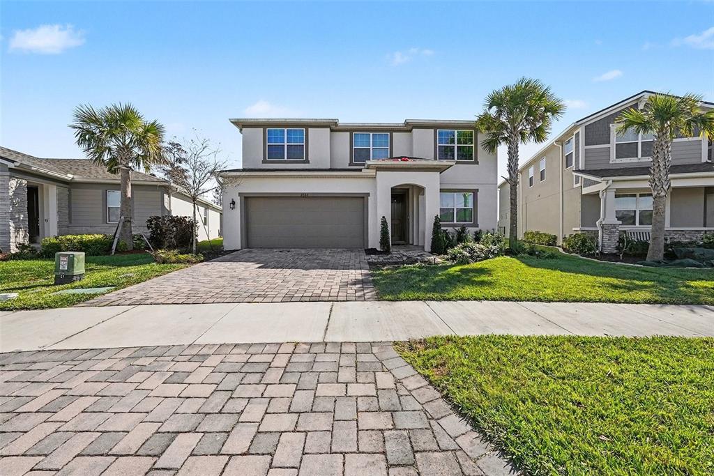 A two-story house with a paved driveway, a two-car garage, and two palm trees — 2326 VILLAGE AMBLE LOOP, LUTZ, FL