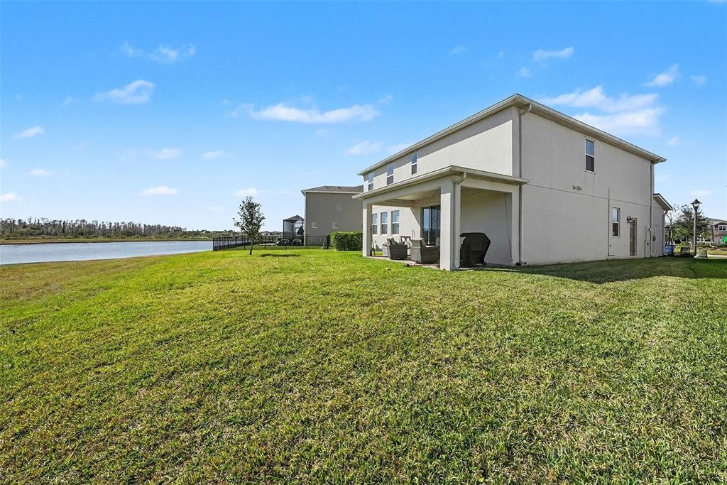 A two-story house with a covered patio overlooks a lake and grassy backyard — 2326 VILLAGE AMBLE LOOP, LUTZ, FL
