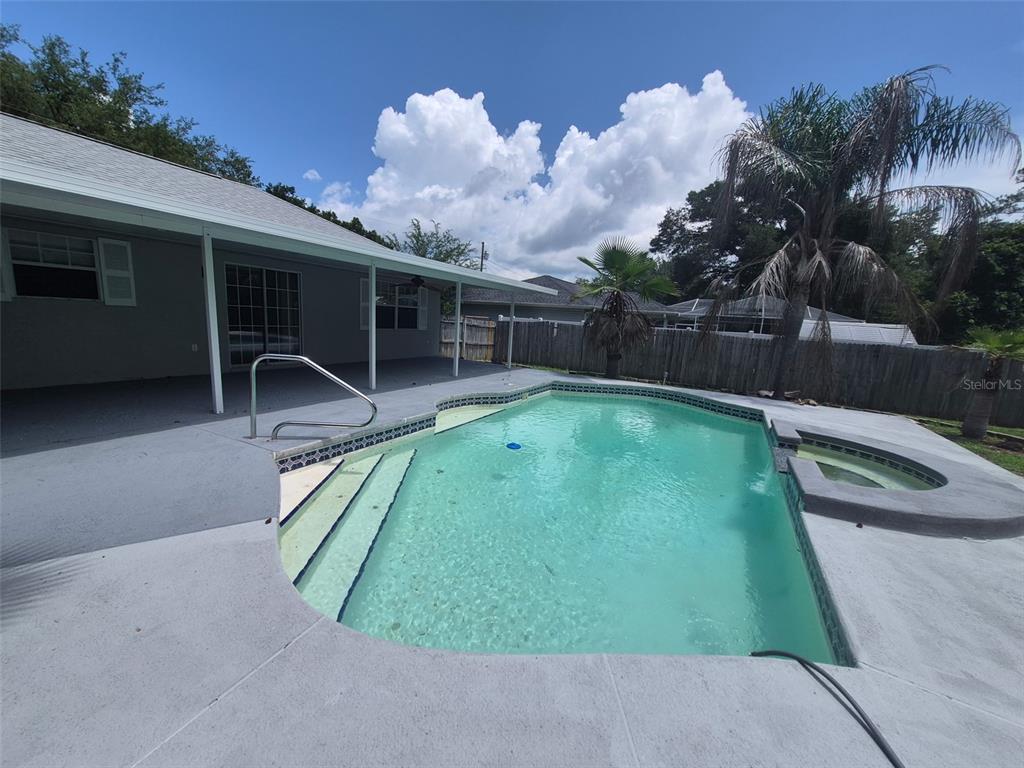 A backyard features a swimming pool with a spa and a covered patio area — 9 TEAK WAY DRIVE, OCALA, FL
