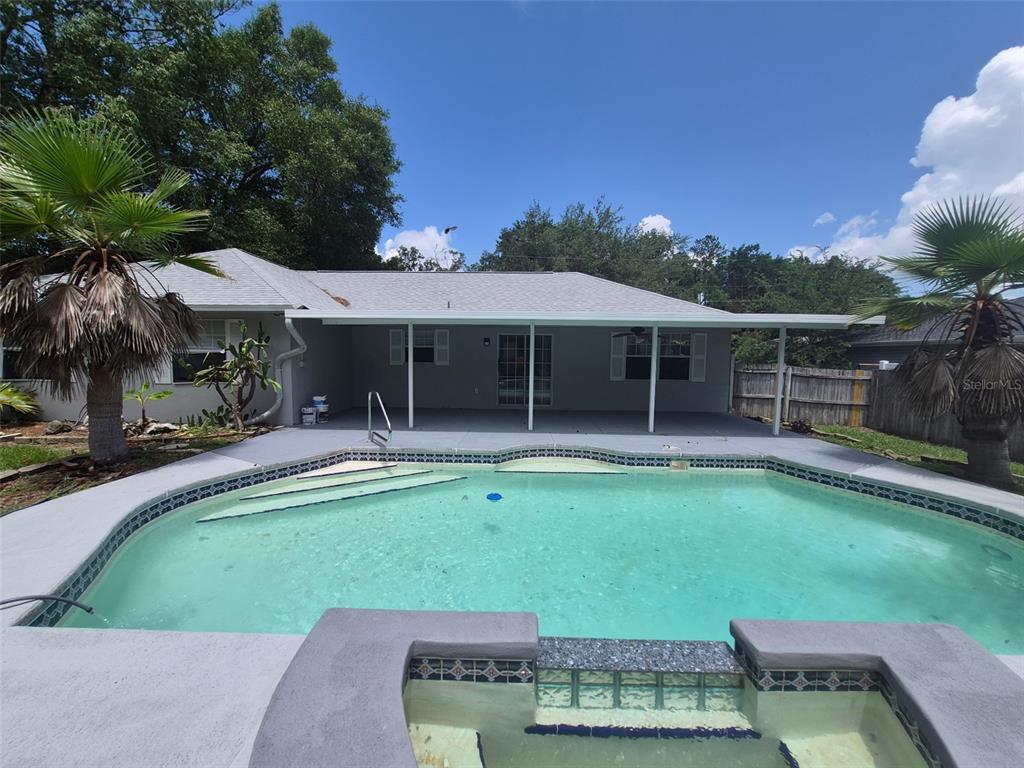 A backyard features a swimming pool, a hot tub, and a covered patio area — 9 TEAK WAY DRIVE, OCALA, FL