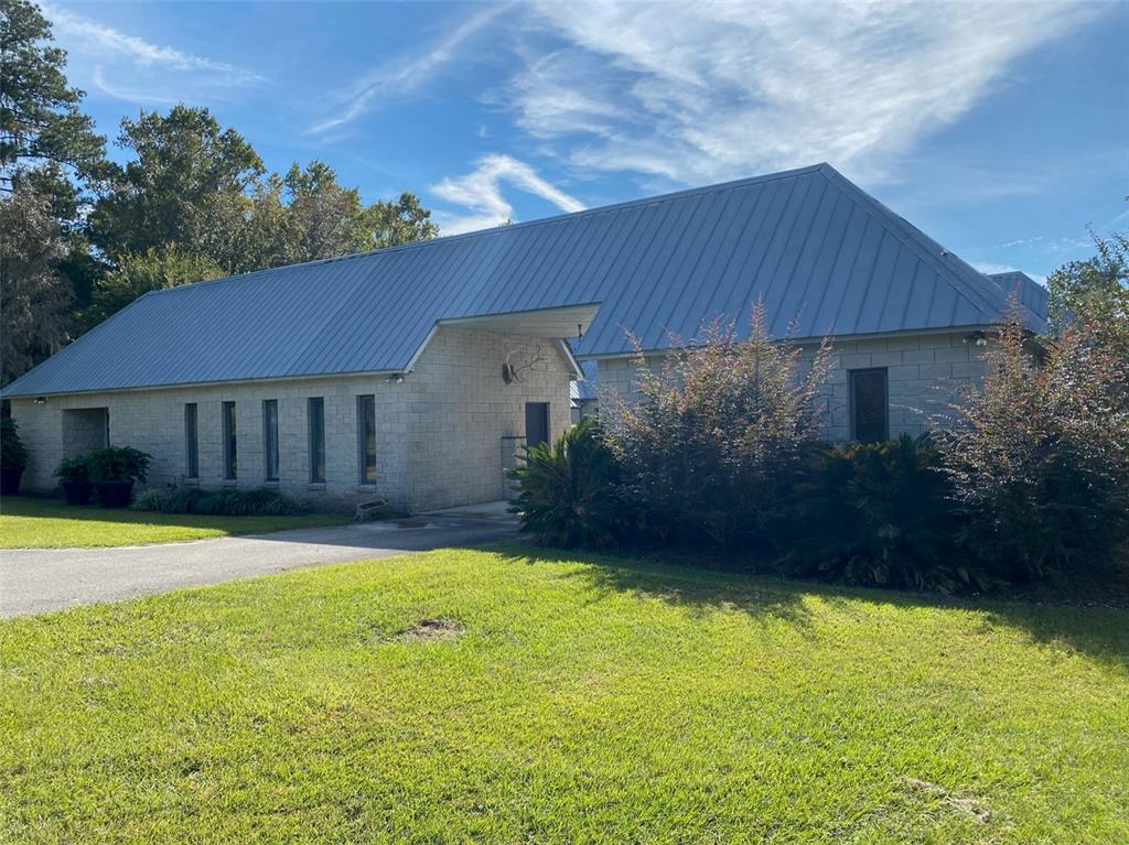 A single-story building with a metal roof and light-colored block exterior sits on a lawn — 19350 NW 123RD COURT, MICANOPY, FL