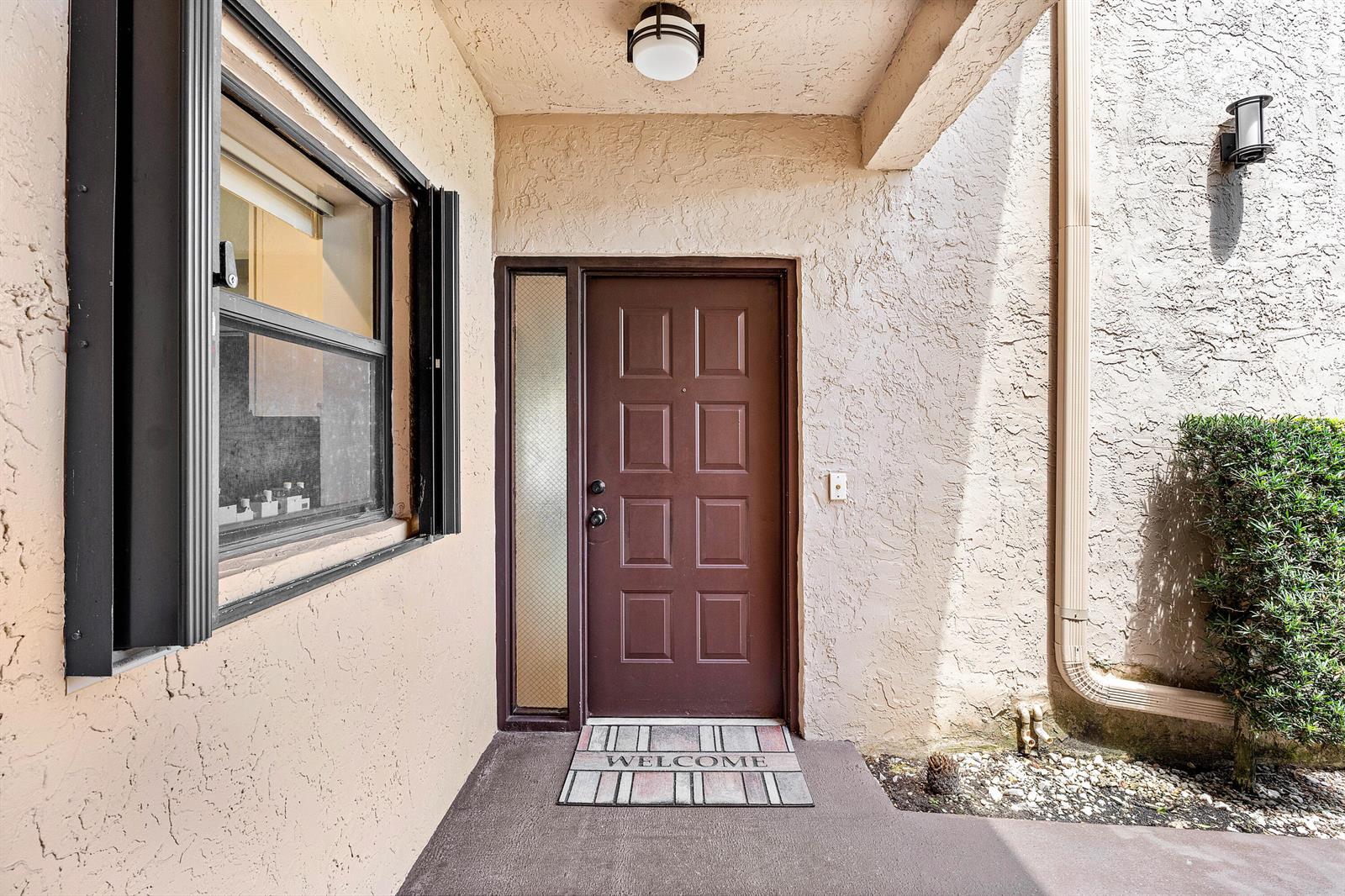 A brown front door with a side window sits under a covered entryway — 8609 Boca Glades Boulevard W # A, Boca Raton FL 33434, BOCA RATON, FL