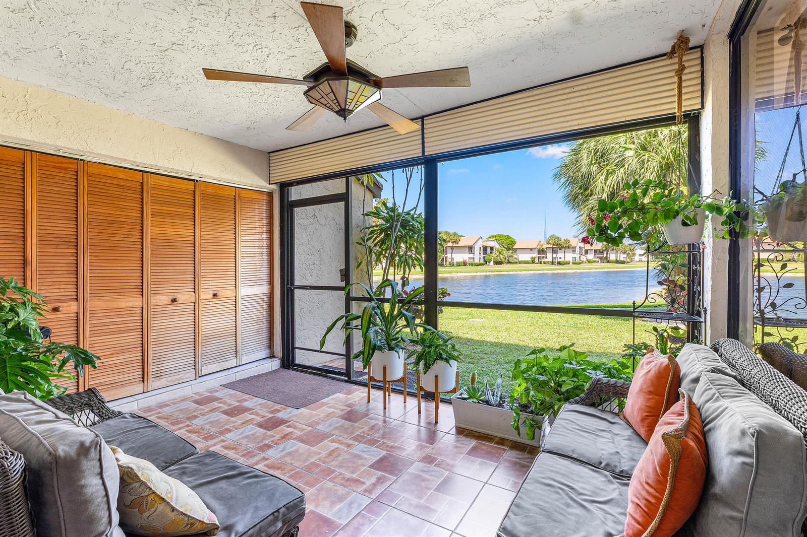 A screened-in porch with tiled floors, a ceiling fan, and views of a lake — 8609 Boca Glades Boulevard W # A, Boca Raton FL 33434, BOCA RATON, FL