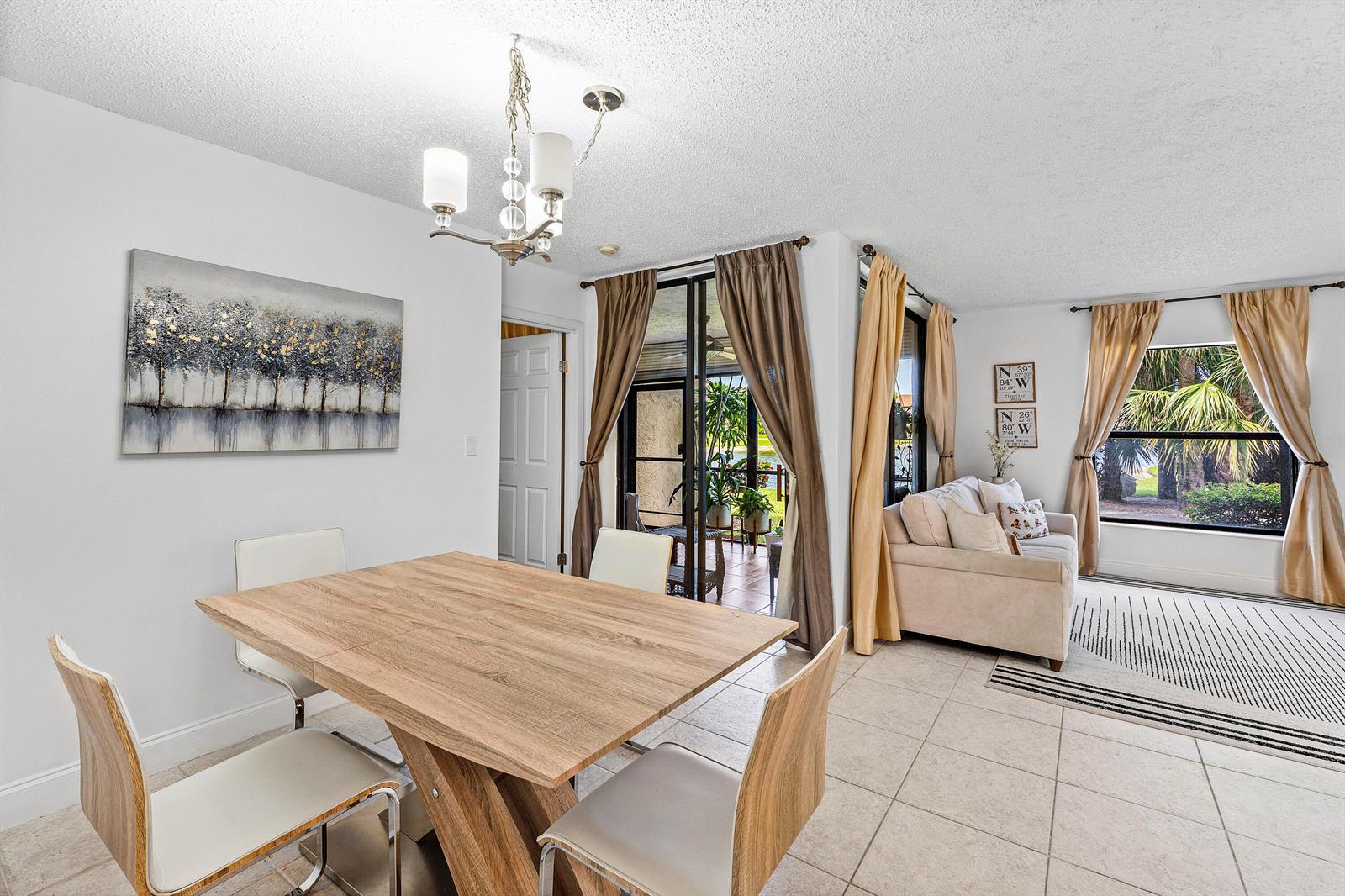 A dining area with a wood table and chairs opens to a living room and patio — 8609 Boca Glades Boulevard W # A, Boca Raton FL 33434, BOCA RATON, FL