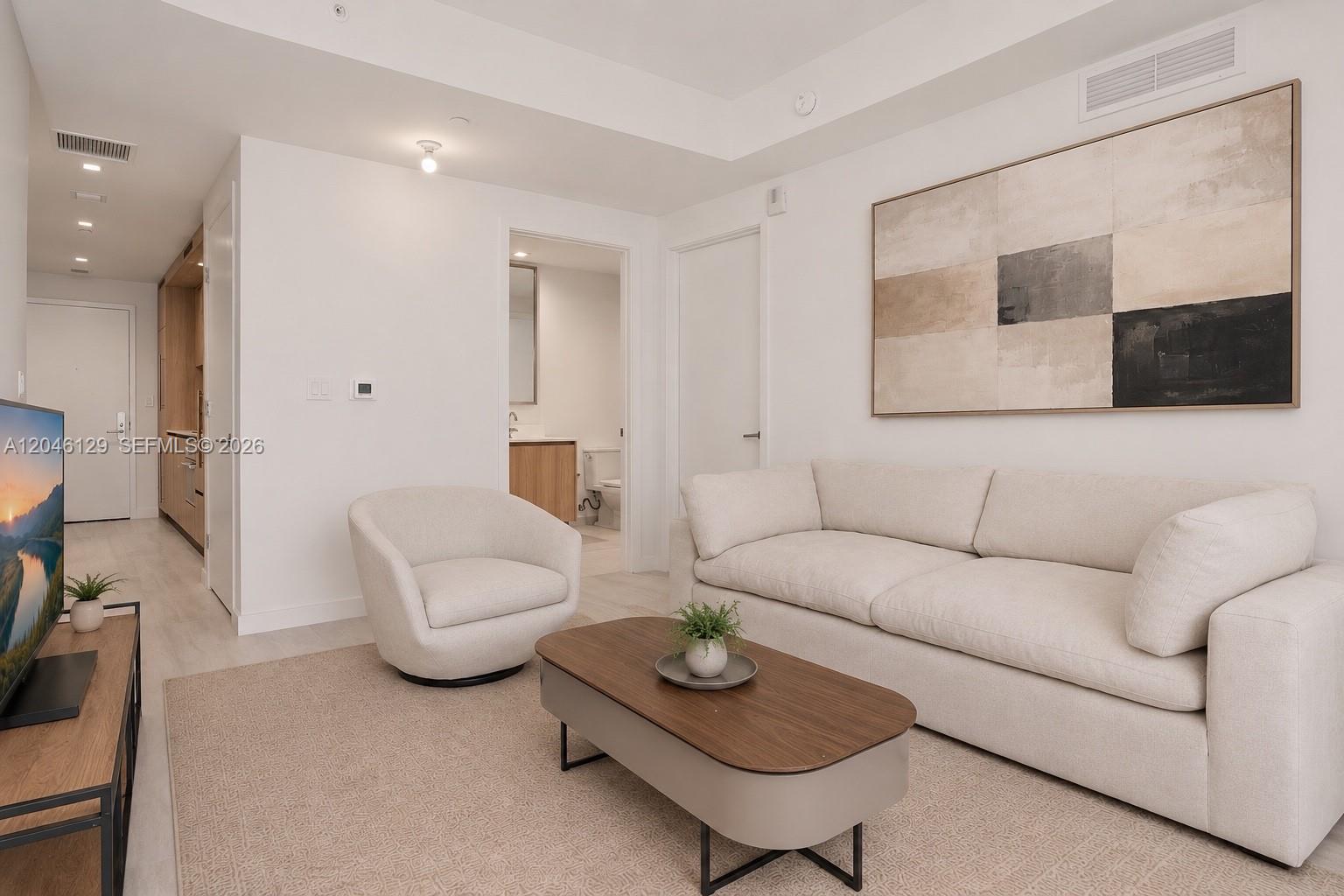 A modern living room features a beige sofa, a swivel chair, and a coffee table — 77 SE 5th St. # 1905, Miami FL 33131, MIAMI, FL