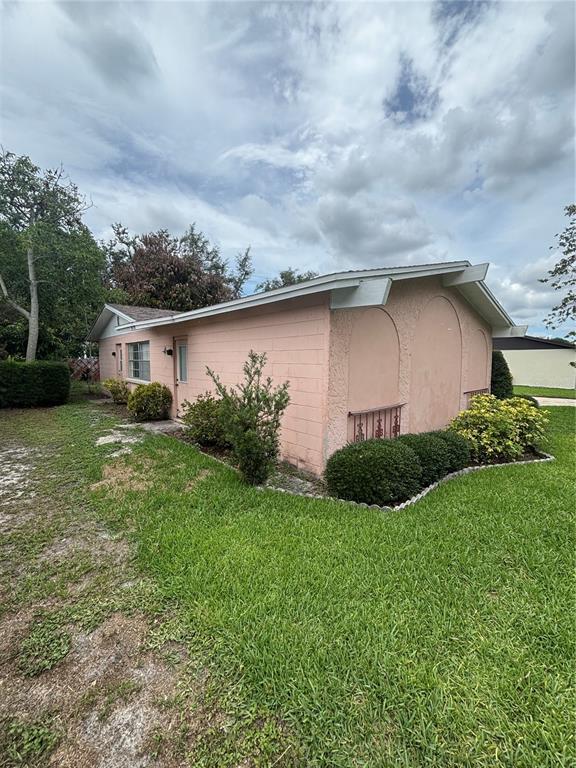 A pink, single-story concrete block house with arched wall details and a grassy yard — 2709 E 122ND AVENUE, TAMPA, FL