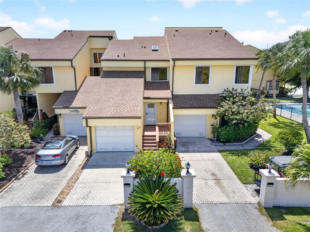 An exterior view of a multi-unit residential building with beige siding and attached garages — 25188 MARION AVENUE UNIT 1006, PUNTA GORDA, FL