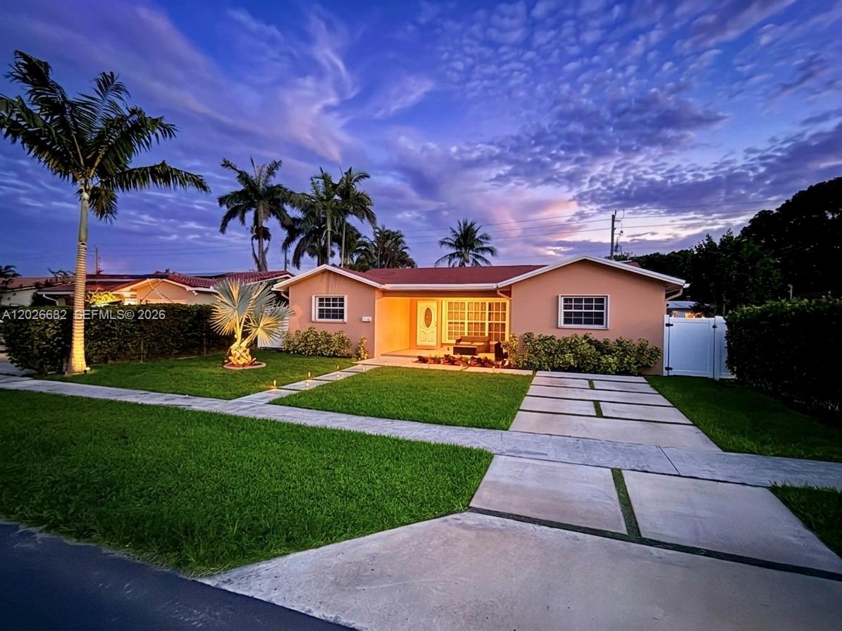 A single-story peach-colored house with a concrete driveway and palm trees at dusk — 206 SE 3rd Pl, Dania Beach FL 33004, DANIA BEACH, FL